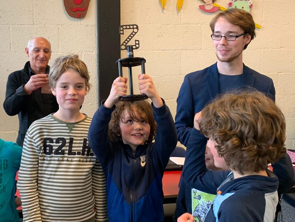 Een speler toont trots de gewonnen trofee. Rechts op de foto Gino de Mon.