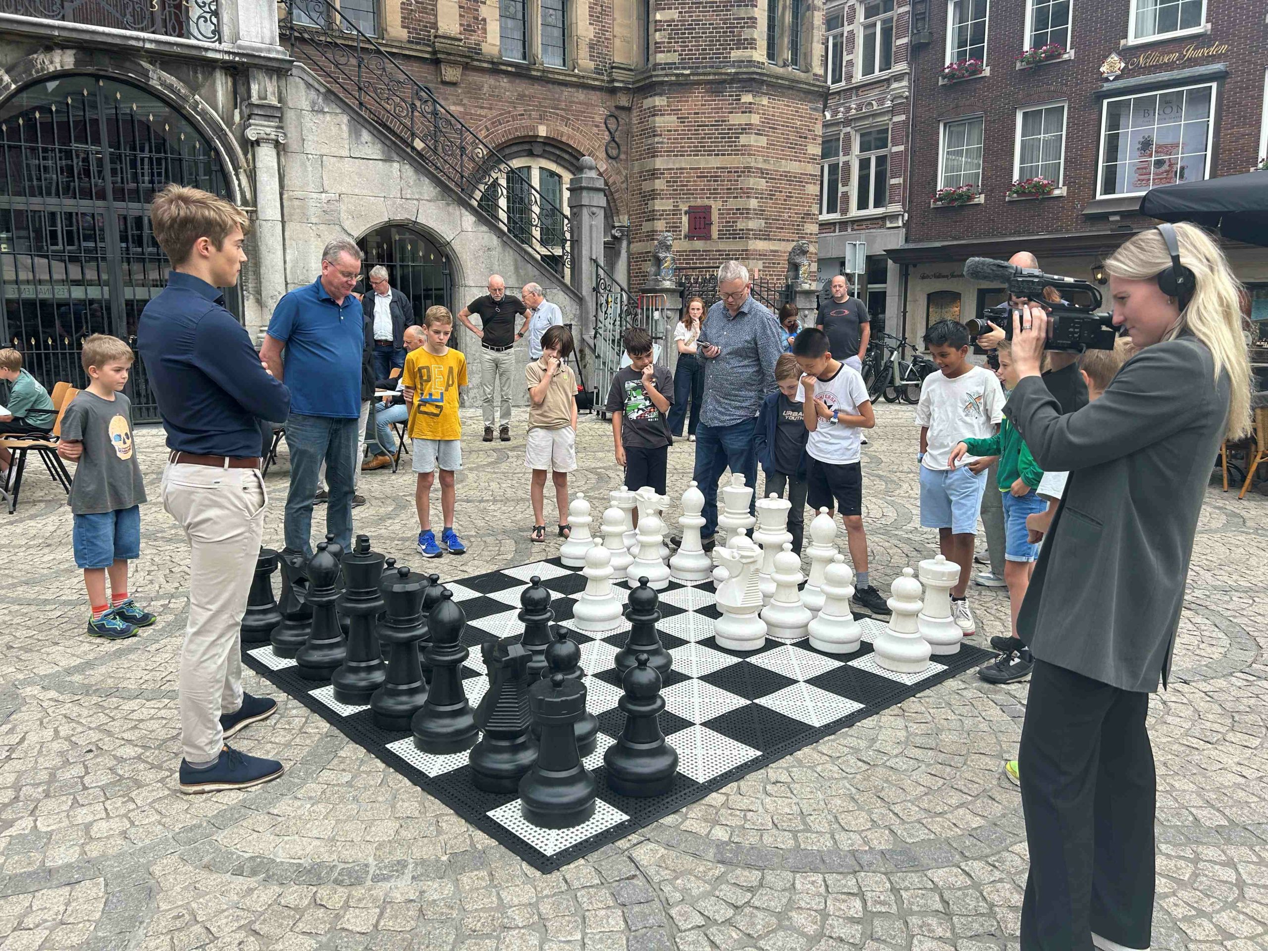 Kampioen van Nederland Max Warmerdam schaakt op de Markt in Venlo tegen een groepje jeugdspelers. (foto Frank Clevers)